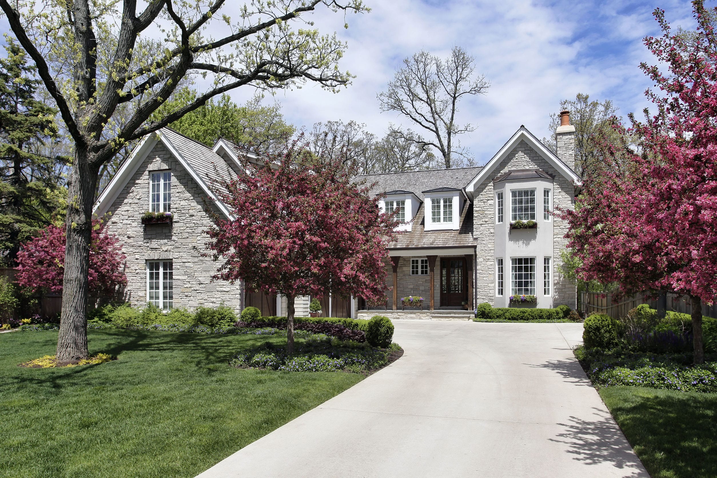 stone home in suburbs with flowering trees